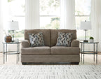 Light beige fabric loveseat with two geometric patterned pillows