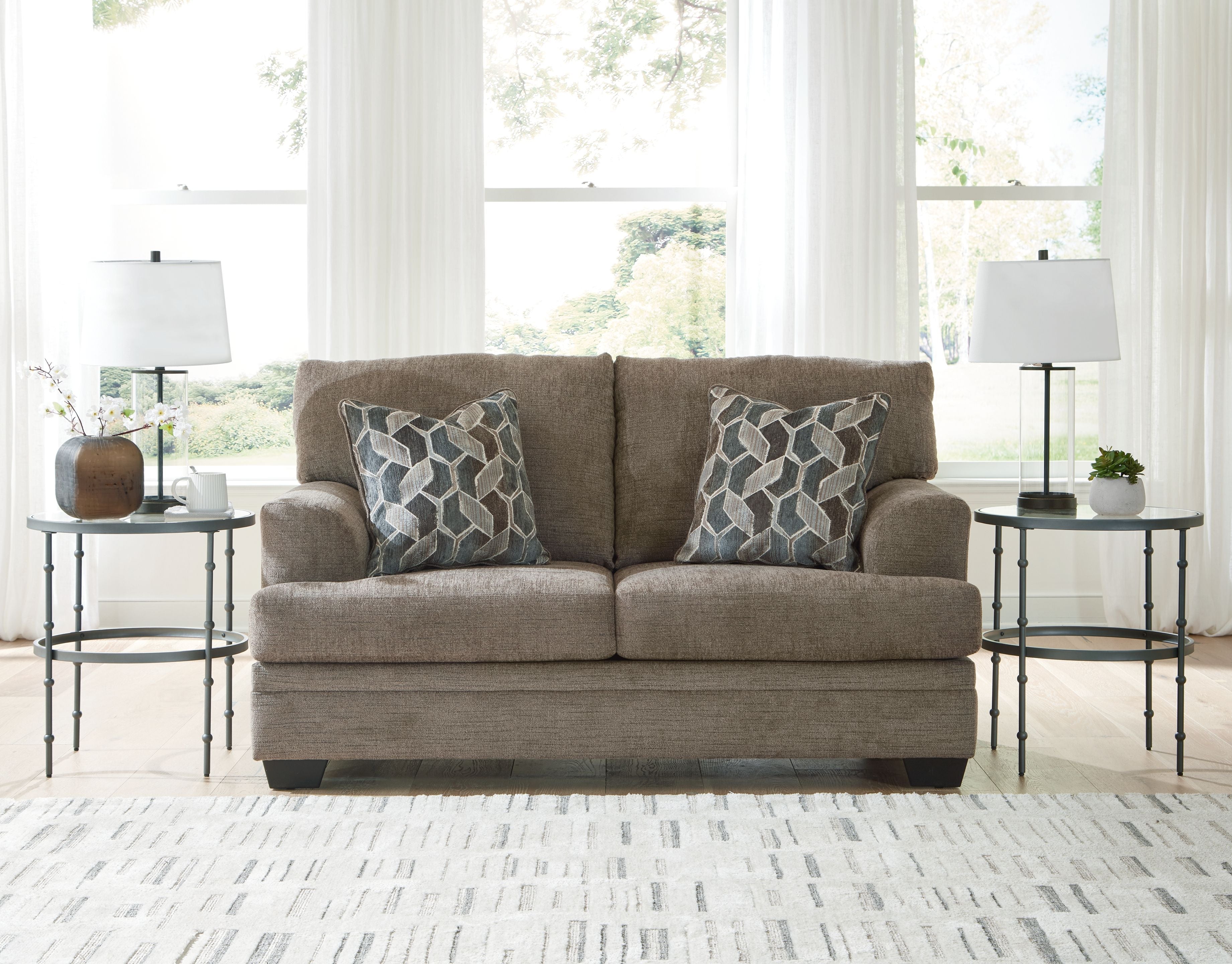 Light beige fabric loveseat with two geometric patterned pillows