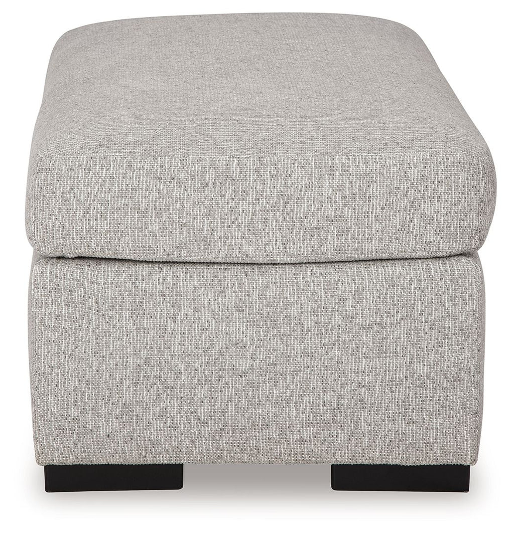 Light gray upholstered ottoman with rounded cushioned top and dark legs
