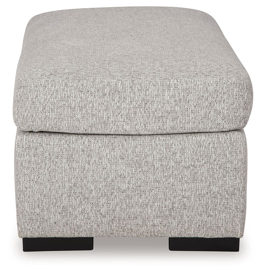 Light gray upholstered ottoman with rounded cushioned top and dark legs