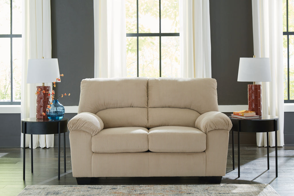 Beige corduroy loveseat with rolled arms, tufted back cushions, and dark feet