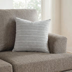 Gray striped throw pillow with thin horizontal lines on a cushioned seat