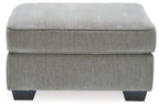 Light gray upholstered accent ottoman with smooth padded seat and short block legs