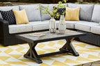 Rectangular cocktail table with black base and light gray top, styled with flowers