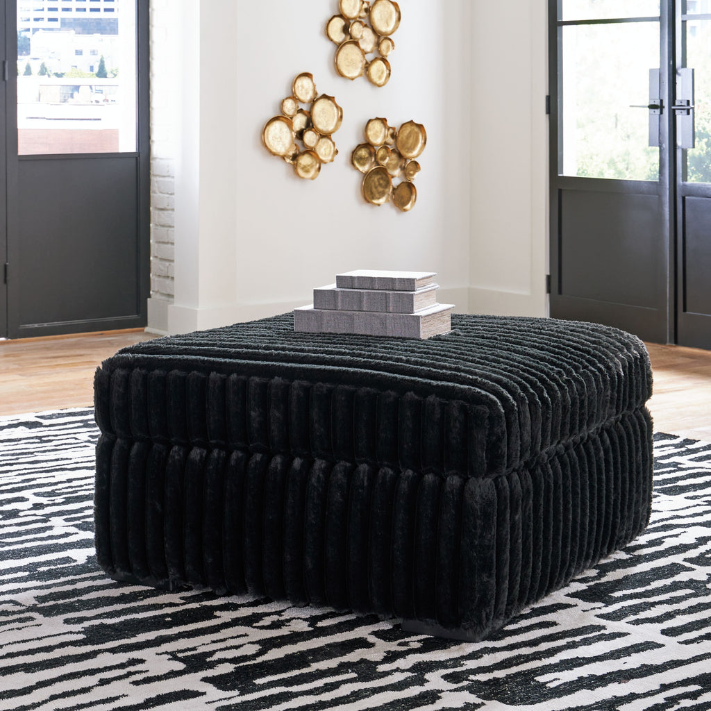 Dark corduroy ottoman with rounded top and vertical channel stitching