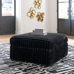 Dark corduroy ottoman with rounded top and vertical channel stitching