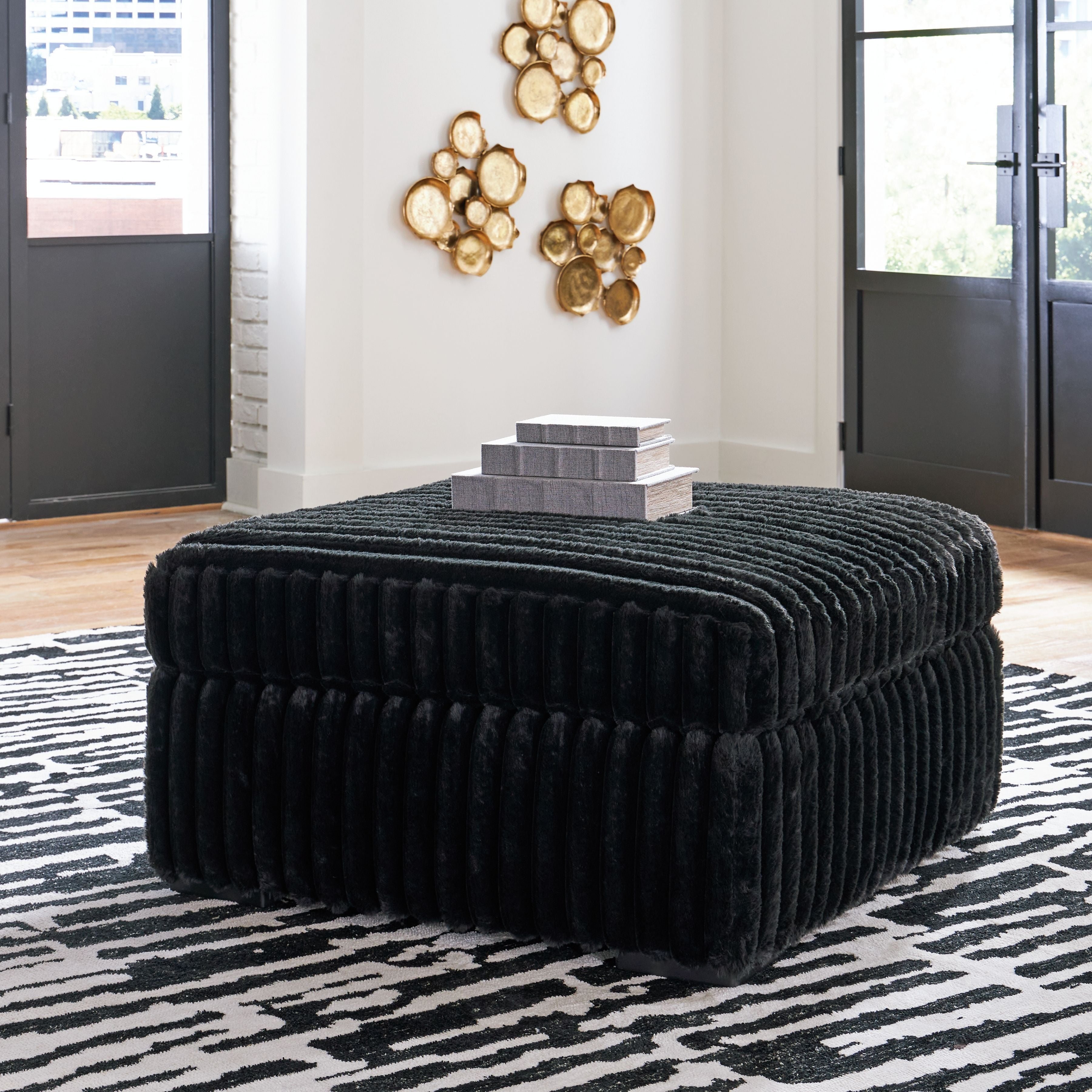 Dark corduroy ottoman with rounded top and vertical channel stitching
