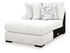 Chalk corner chaise with padded arm, deep seat, and two patterned throw pillows