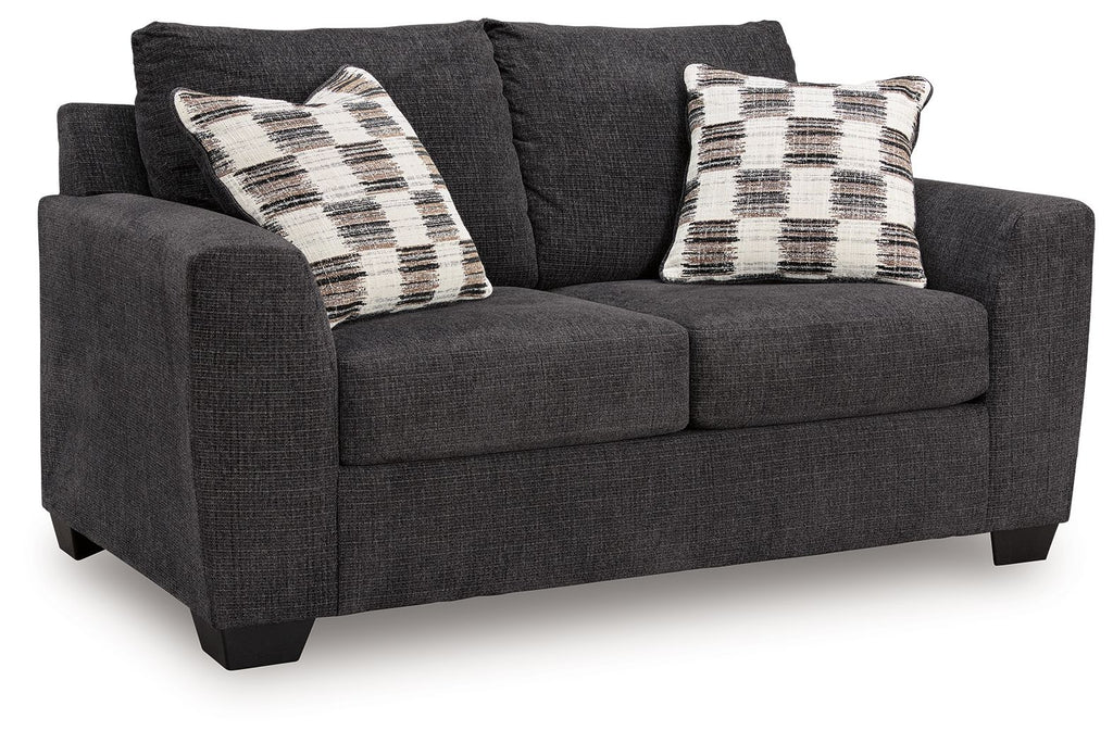 Dark gray loveseat with two plaid throw pillows and padded rolled arms