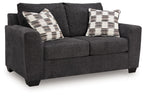 Dark gray loveseat with two plaid throw pillows and padded rolled arms