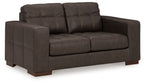 Dark brown loveseat with tufted back cushions and wide padded armrests