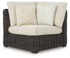 Corner sofa chair with beige cushions and dark wicker frame