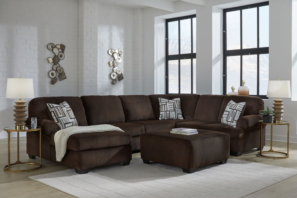 Chocolate sectional sofa with chaise and patterned throw pillows on a living room floor