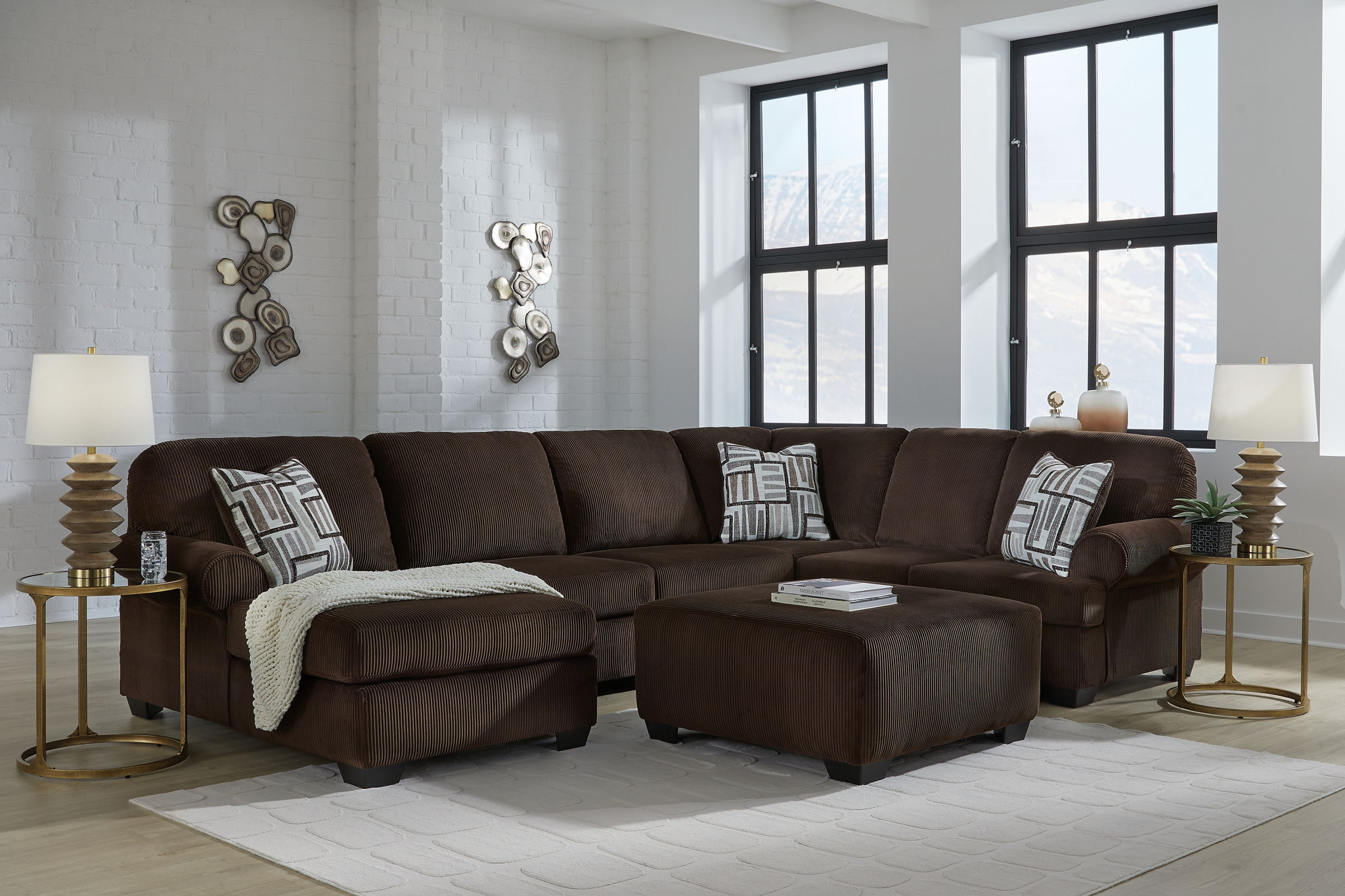 Chocolate sectional sofa with chaise and patterned throw pillows on a living room floor