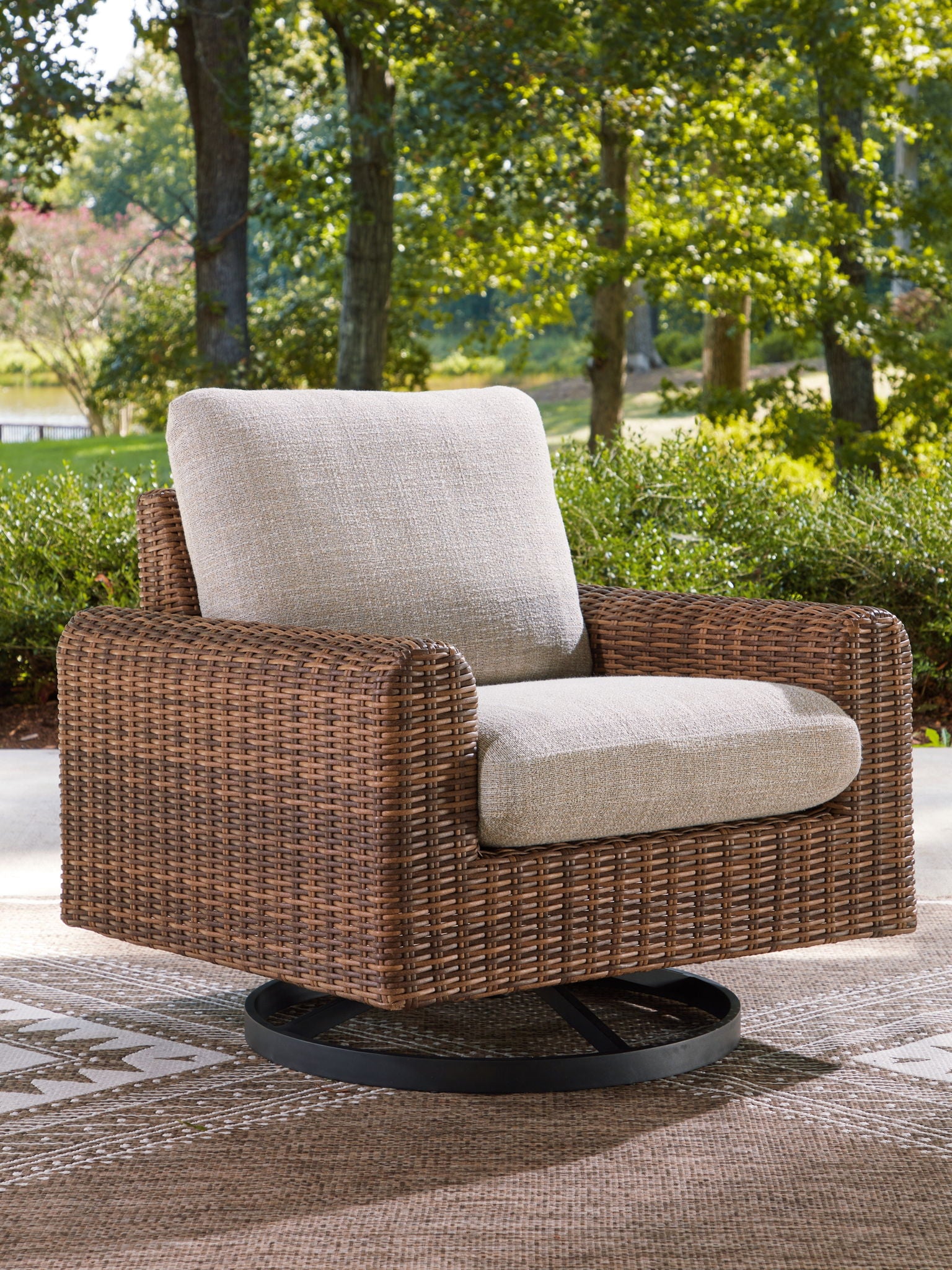 Woven swivel lounge chair with gray cushion, dark brown wicker frame, black circular base