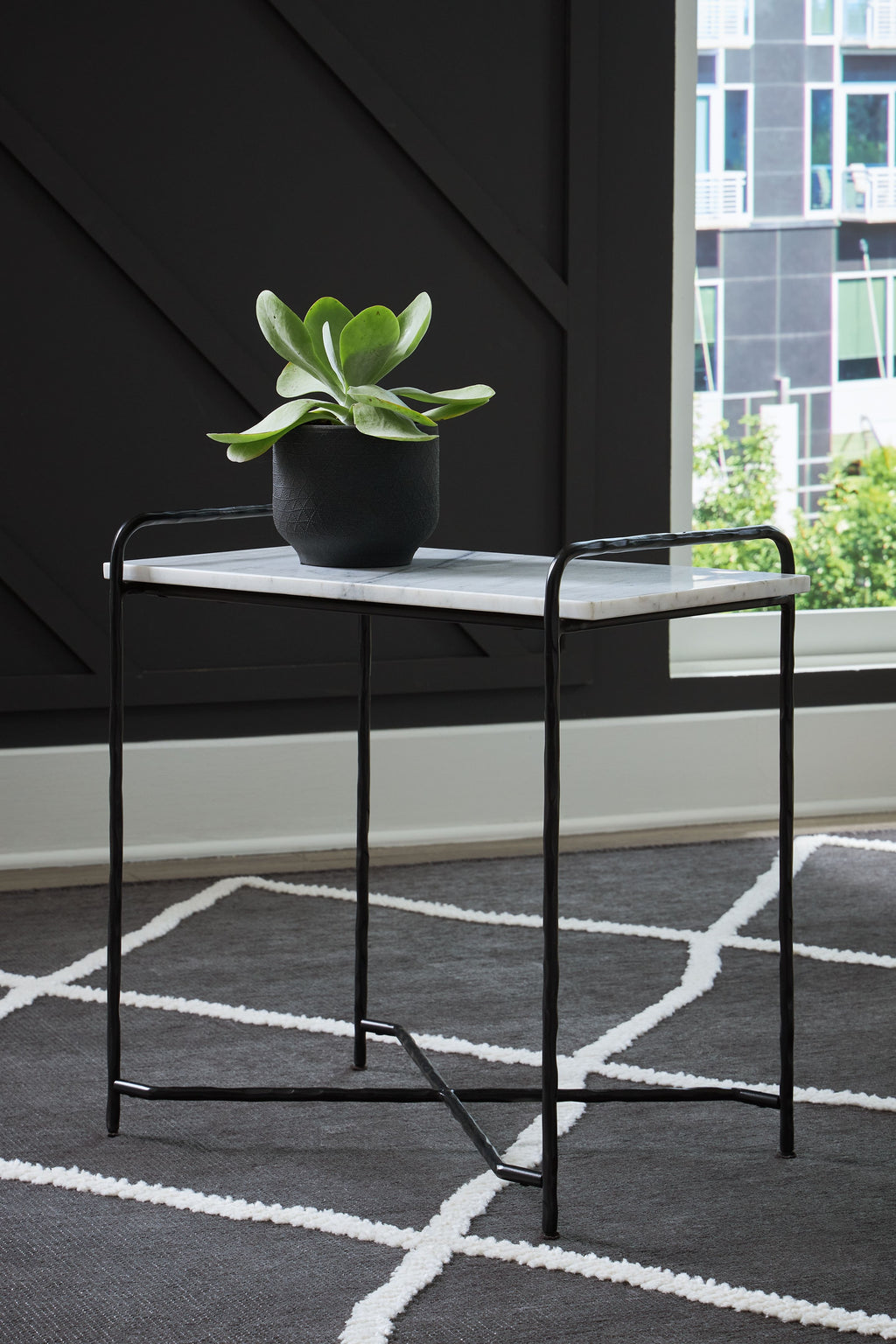 Accent table with white marble-look top, black frame and potted plant on top