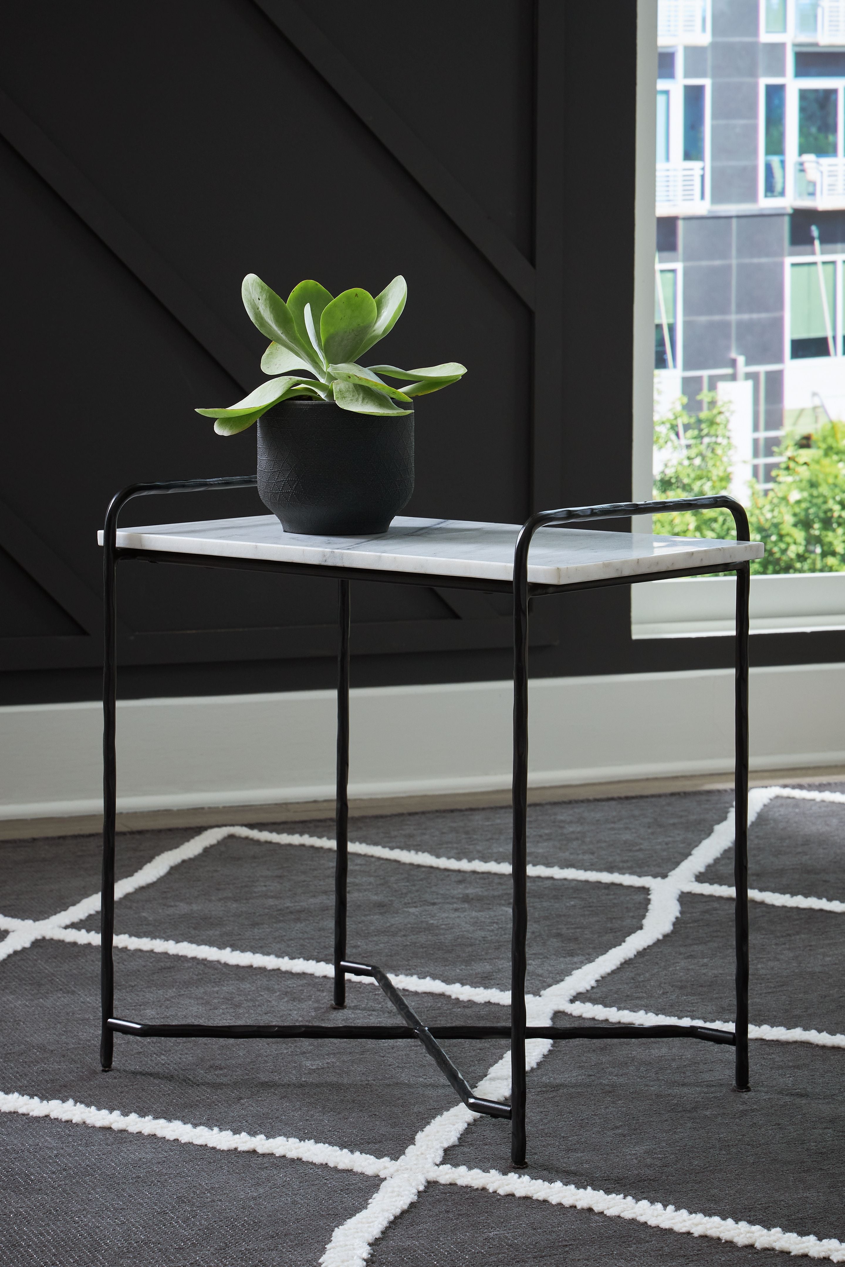 Accent table with white marble-look top, black frame and potted plant on top