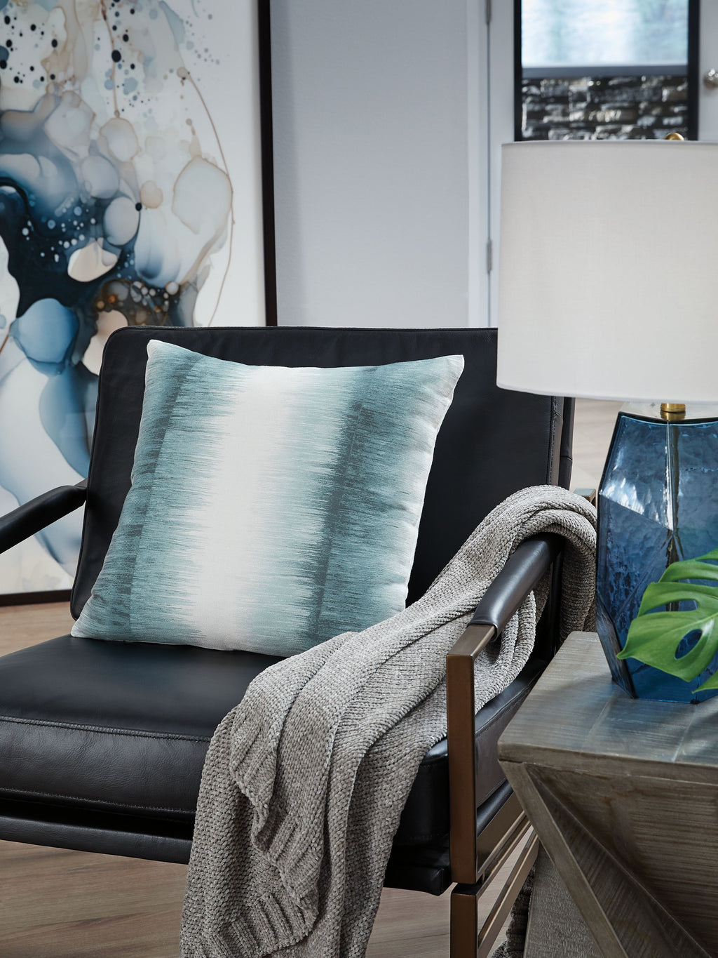 Blue square decorative pillow on sofa with knitted throw draped over arm
