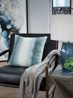 Blue square decorative pillow on sofa with knitted throw draped over arm