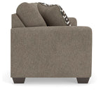 Gray suede sofa arm and back with one black-and-white patterned throw pillow