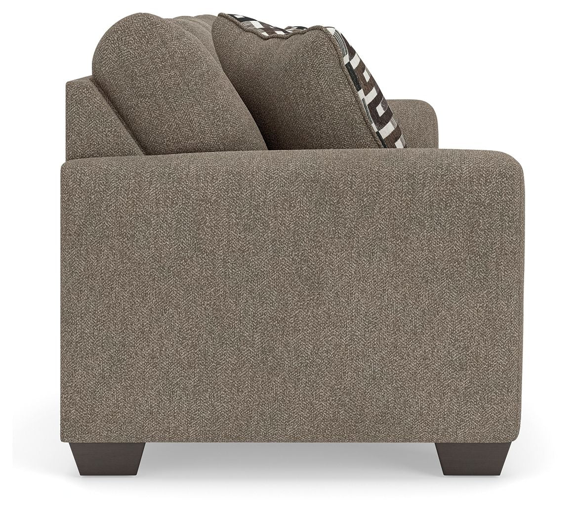 Gray suede sofa arm and back with one black-and-white patterned throw pillow