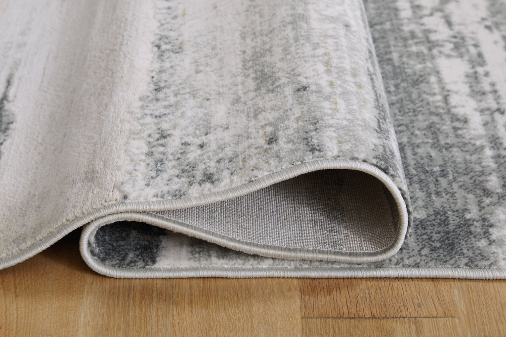 Gray area rug edge with stitched border and low pile