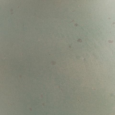 Green ceramic vase surface with mottled speckle pattern
