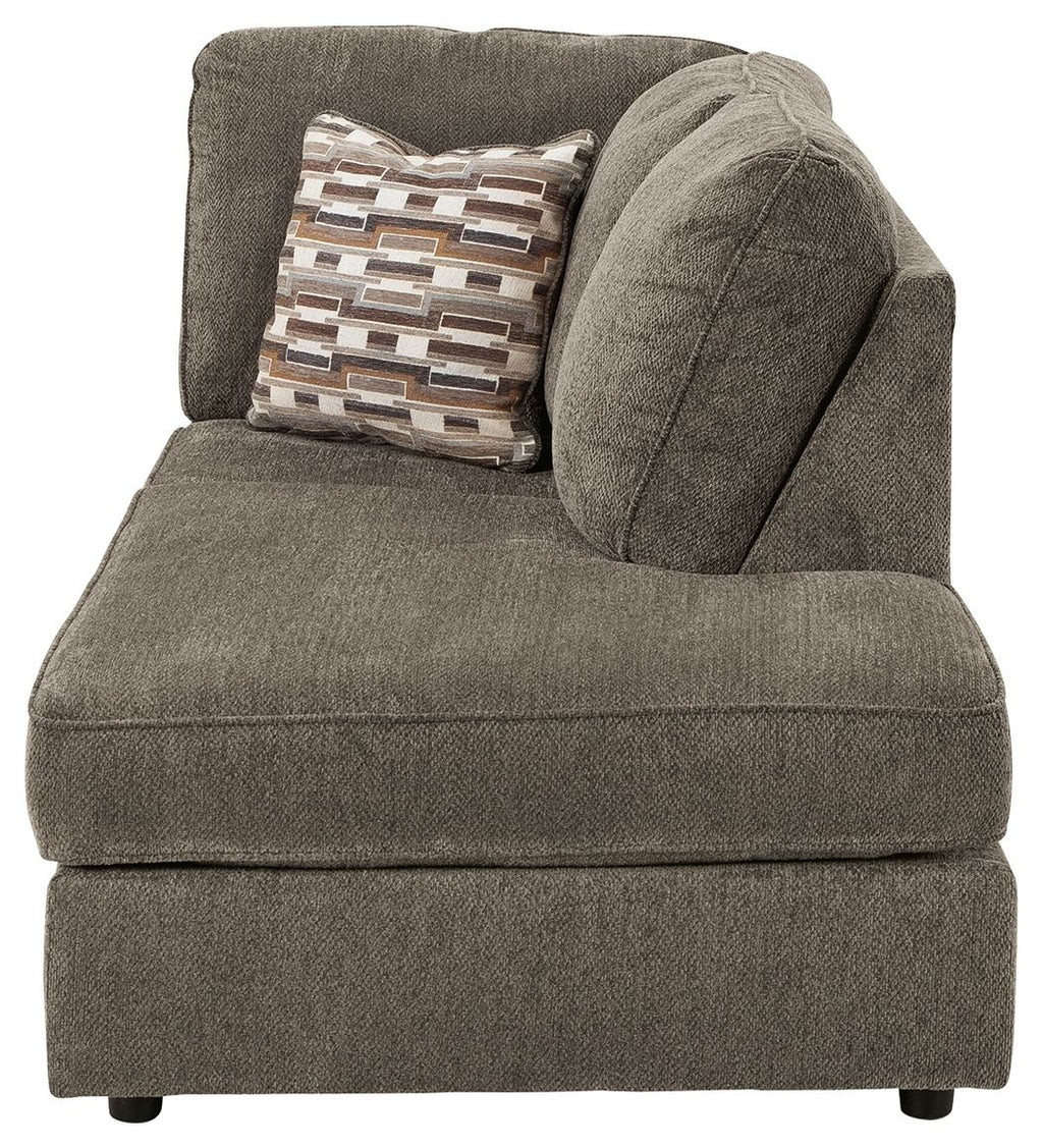 Gray corner chaise with armless seat and large curved back cushion with patterned pillow