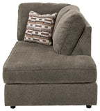 Gray corner chaise with armless seat and large curved back cushion with patterned pillow