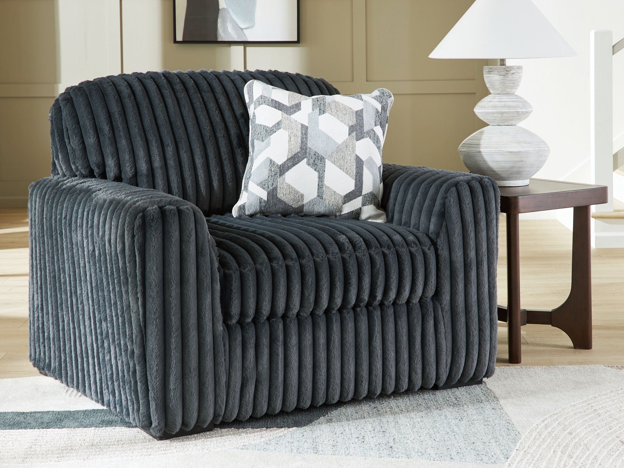 Dark gray chair and a half with geometric pillow and cushioned backrest