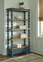Blue bookcase with brown shelves and lower drawer, tall turned posts in an open frame.