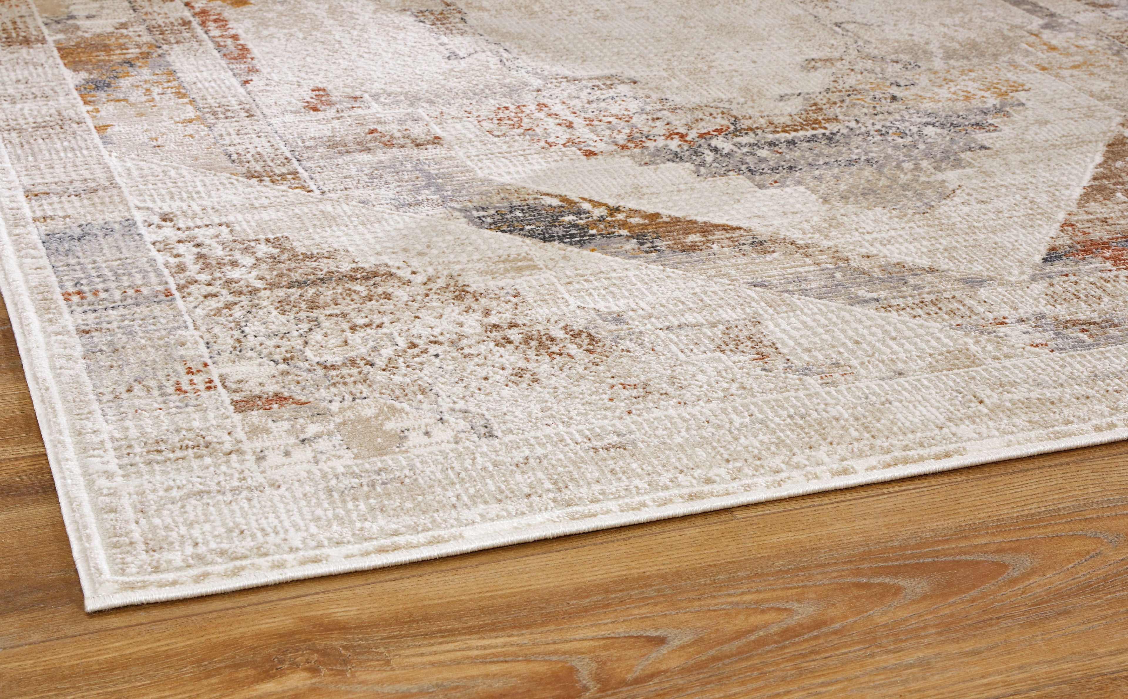 Distressed beige and gray rug corner with textured woven surface.