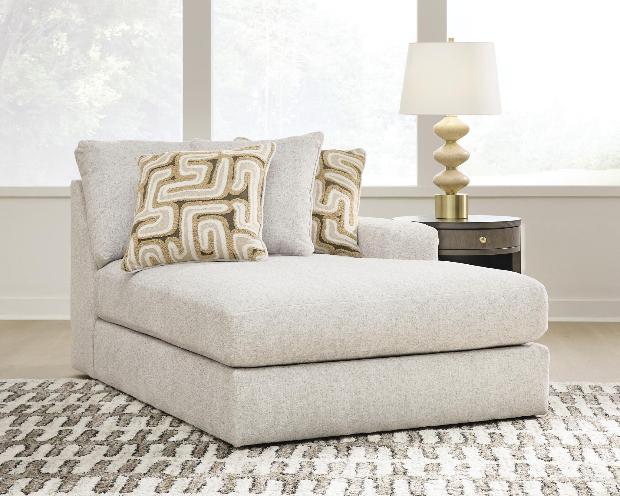 Light beige corner chaise with two patterned cushions and a wide rounded arm