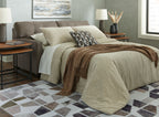Chocolate sofa sleeper with extended bed and quilted bedding in neutral tones