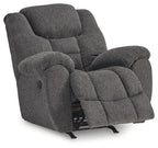 Charcoal fabric rocker recliner with extended footrest and padded armrests, side view