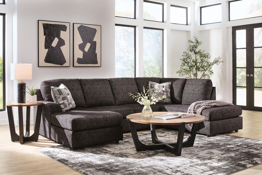 Dark charcoal fabric sectional sofa with chaise, two corner cushions, and three decorative pillows