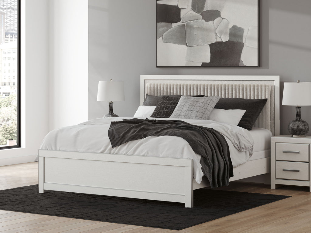 White upholstered panel bed with padded headboard and slatted posts, matching footboard