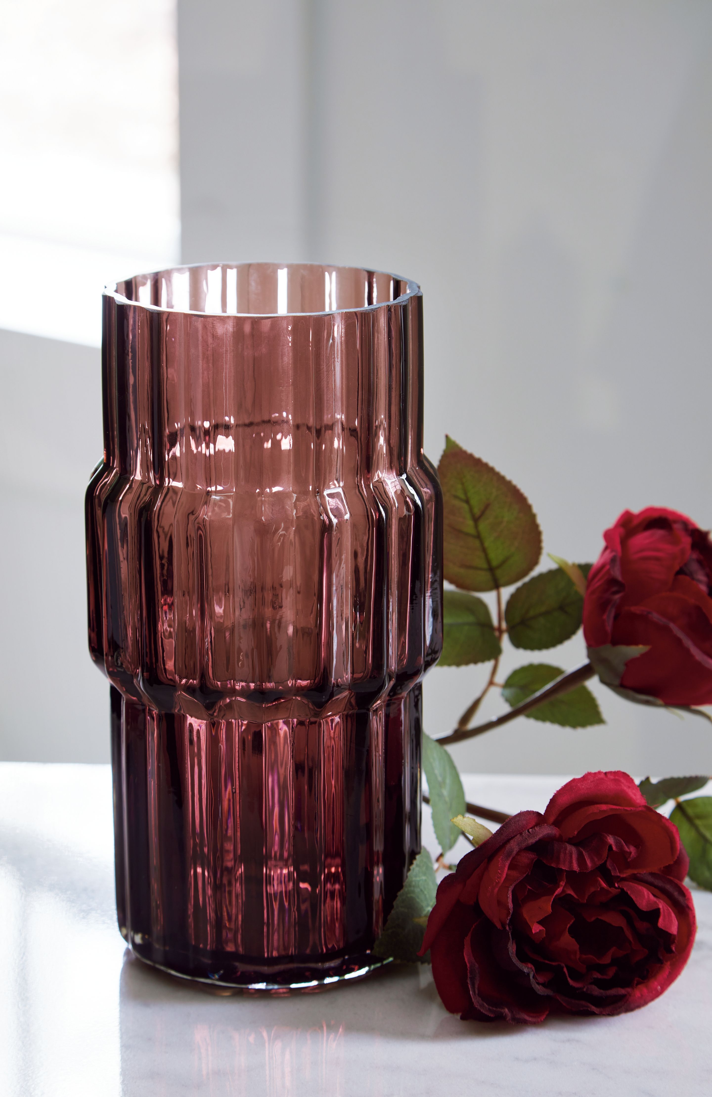Purple glass vase with faceted sides and flared top on tabletop