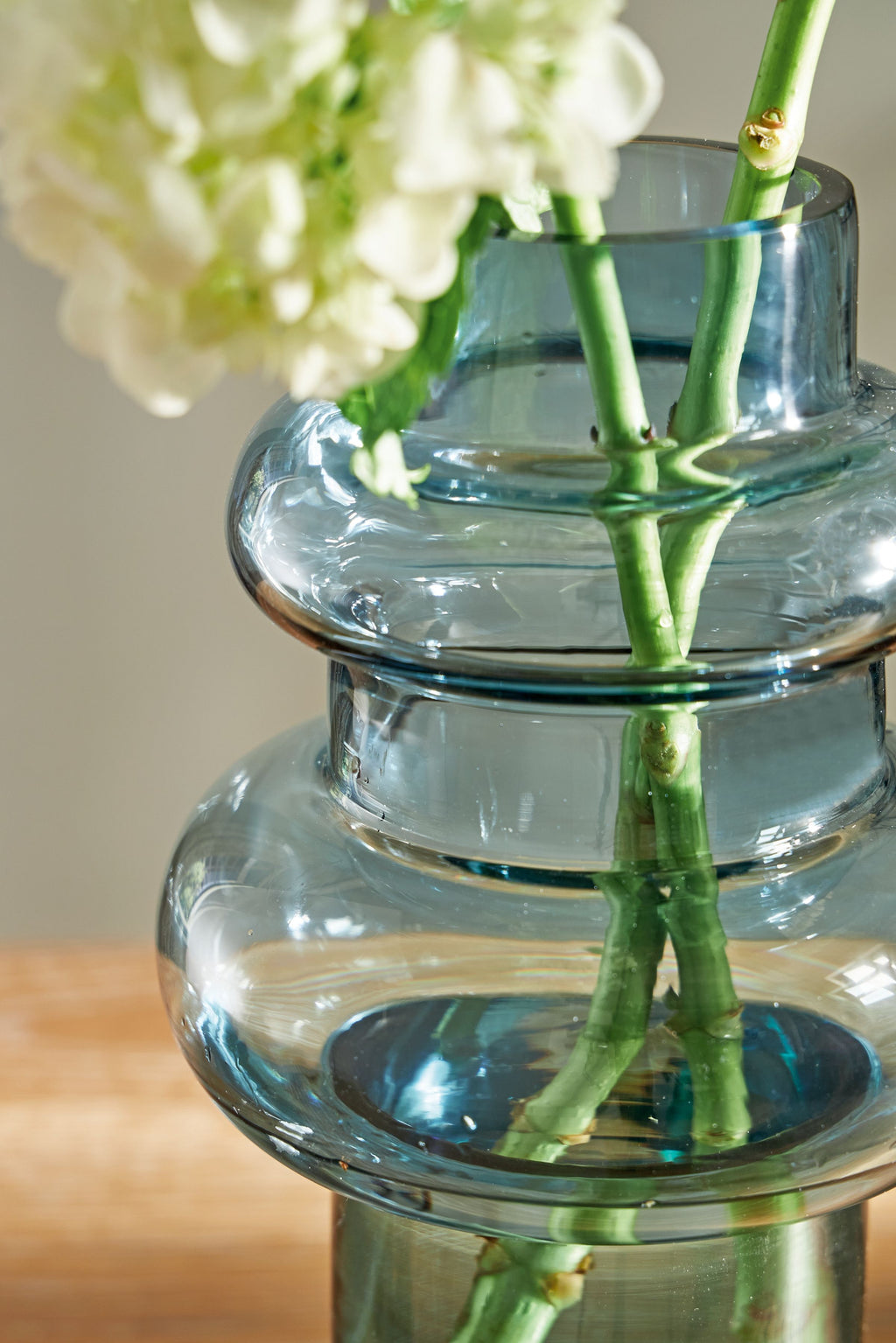 Blue glass vase with green bamboo-like stems and white flowers