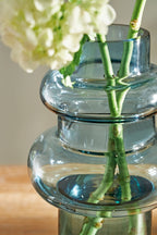 Blue glass vase with green bamboo-like stems and white flowers