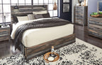 Panel bed with dark wood frame and panel headboard; beige and gray bedding with throw blankets