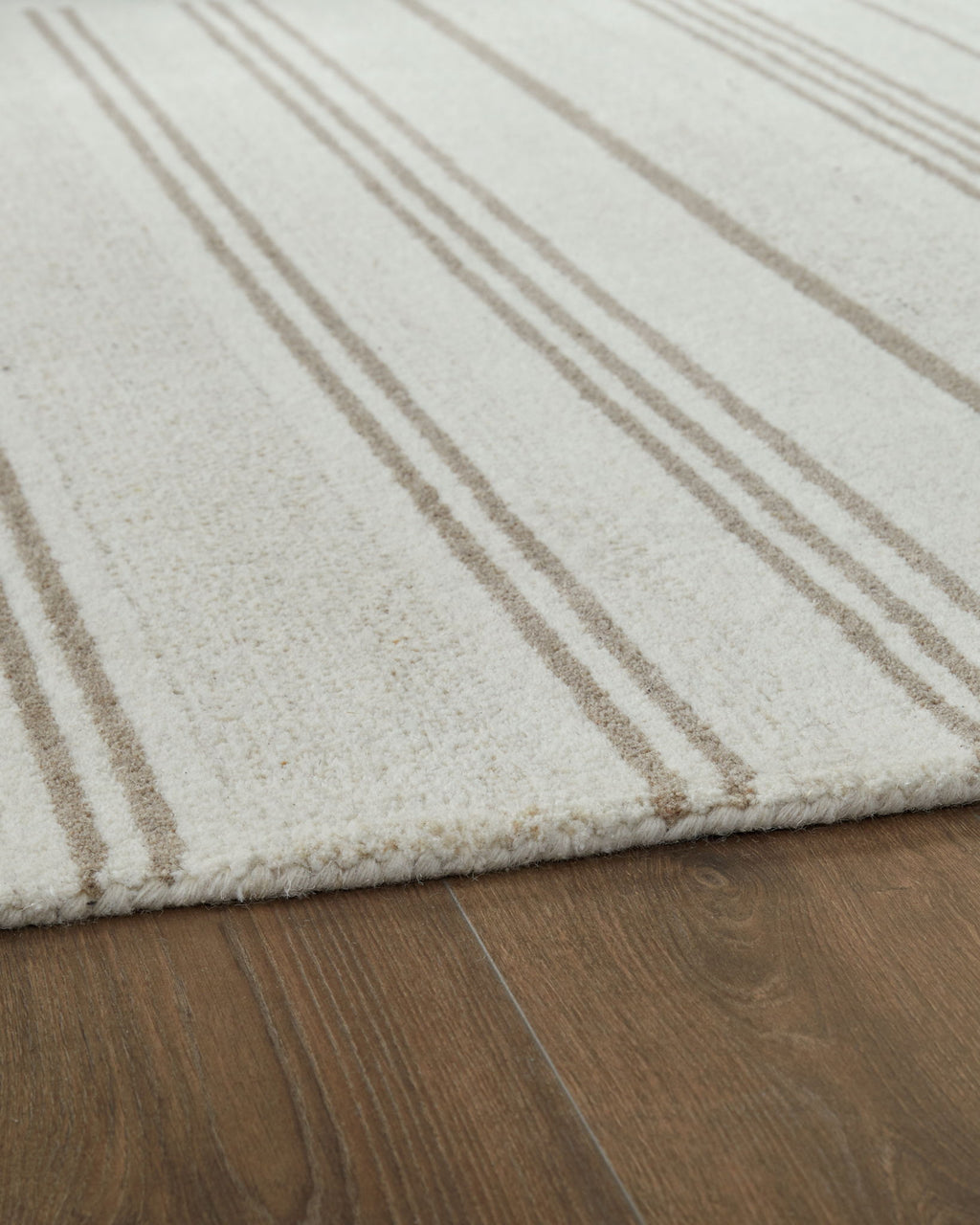Off-white rug corner with beige horizontal stripes and soft textured pile