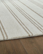 Off-white rug corner with beige horizontal stripes and soft textured pile