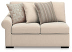 Beige loveseat with two cushioned seat panels, three accent pillows, and dark legs
