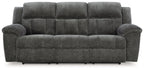 Graphite gray reclining sofa with tufted seat and back, padded rounded arms, and legs
