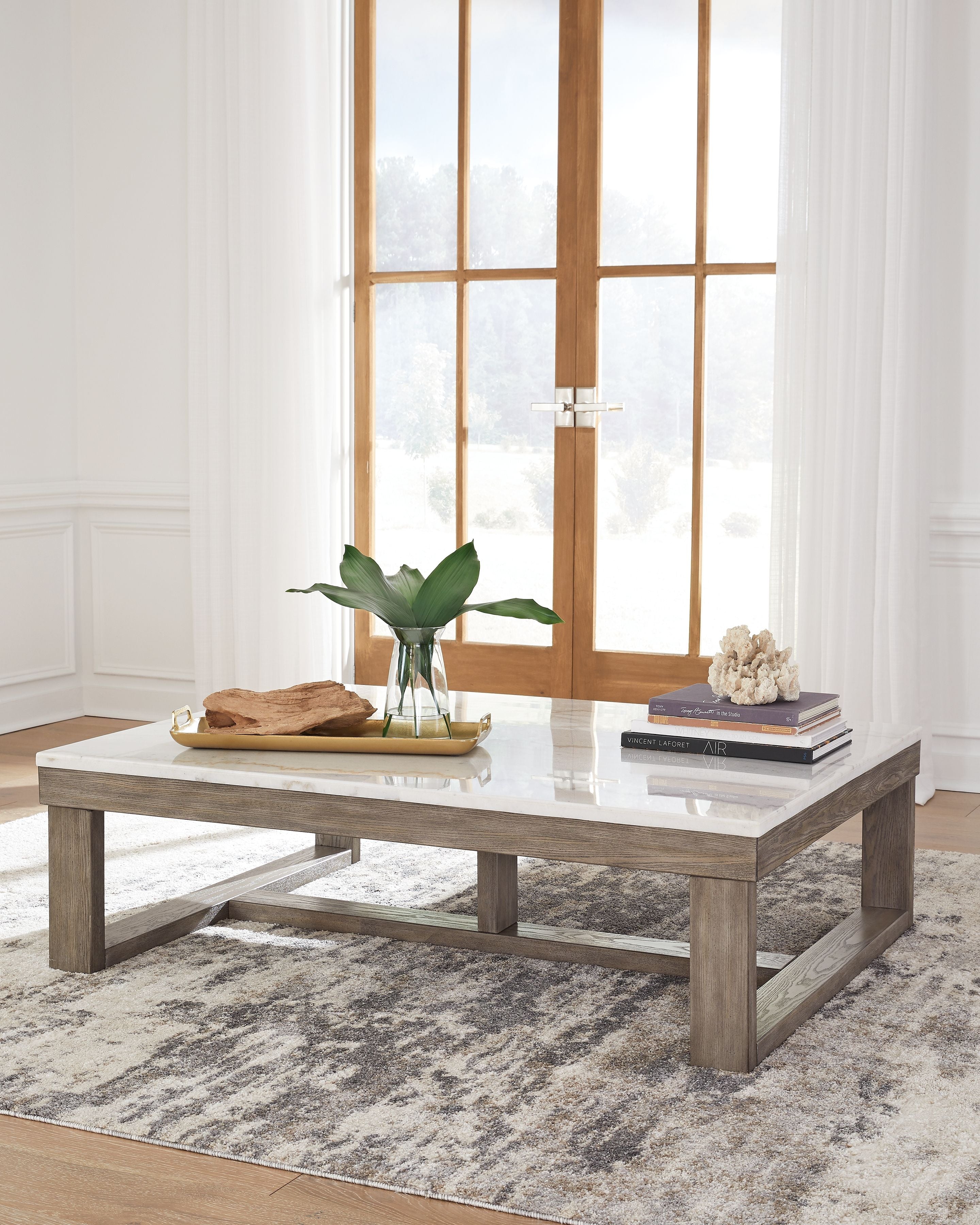 Rectangular cocktail table with white marble-look surface and brown wood base.