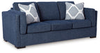 Navy fabric sofa with two patterned throw pillows and thick armrests