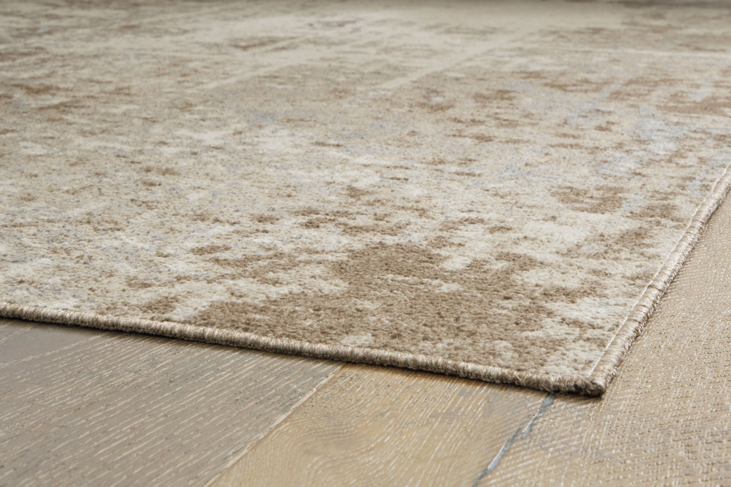 Light brown rug corner with stitched edge and low, plush texture