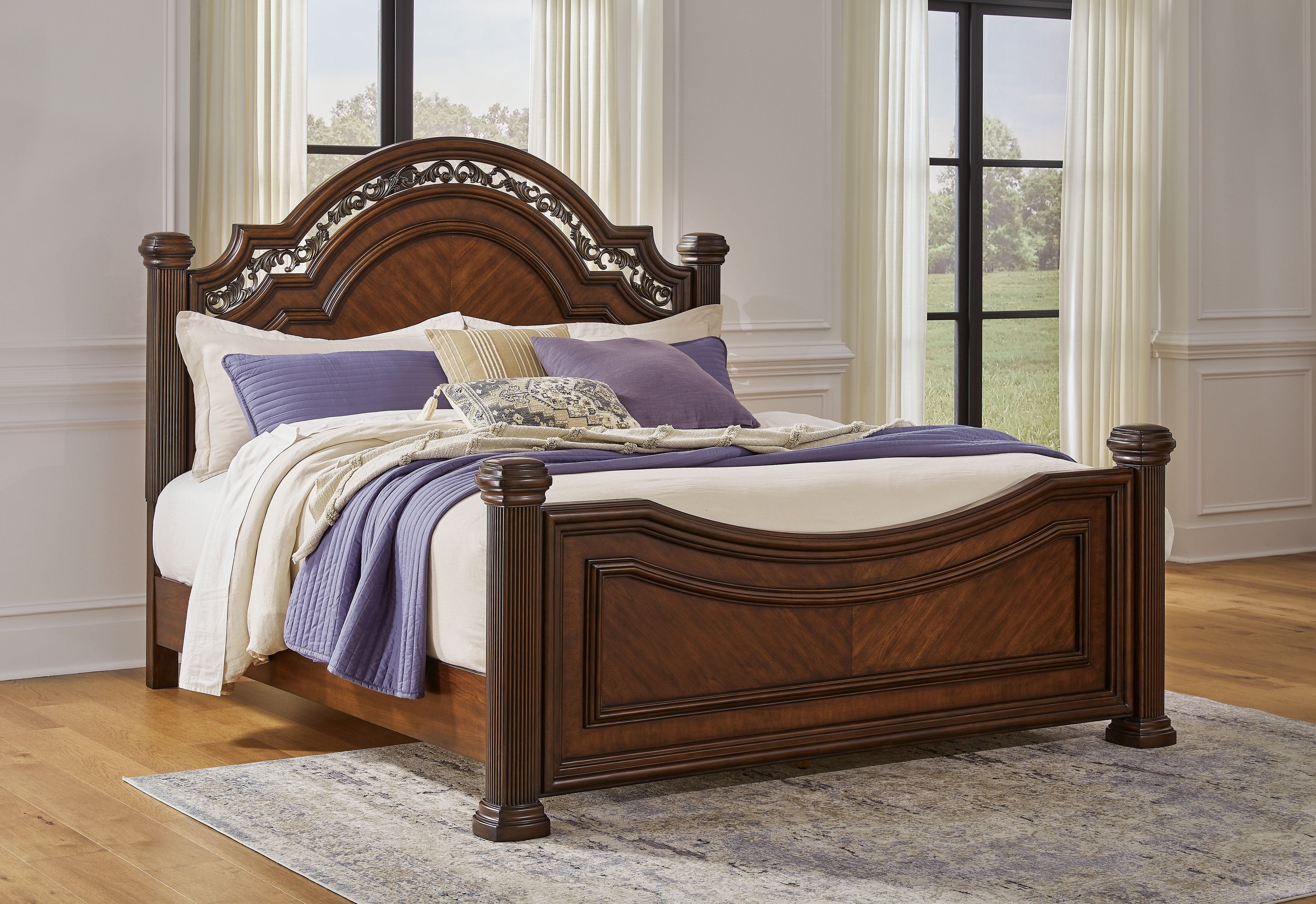 Dark brown poster bed with ornate arched headboard, white bedding and purple coverlet