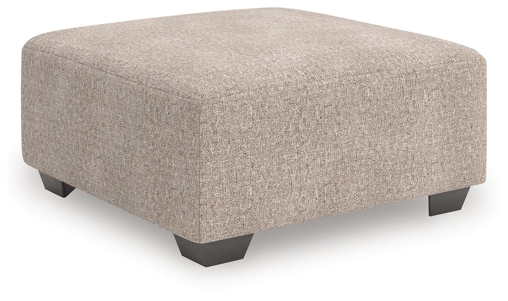 Beige oversized accent ottoman with square padded top and dark legs